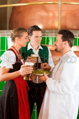 Couple with beer and their brewer in brewery