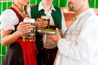 Couple with beer and their brewer in brewery