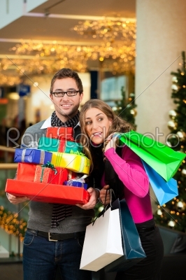 Couple with Christmas presents and bags in shopping mall