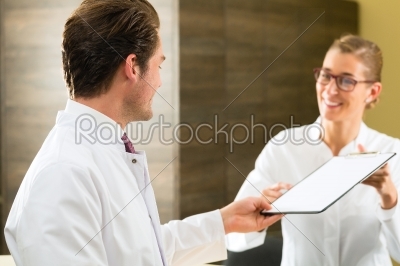 Dentist and nurse with clipboard in clinic
