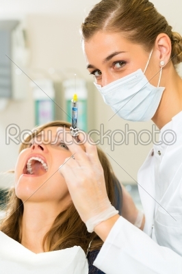 dentist holding a syringe and anesthetizing her patient