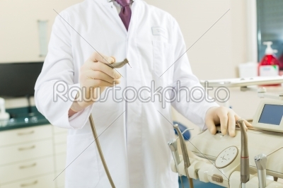 Dentist in his surgery, he holds a drill