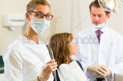 Dentist in his surgery, she holds a drill