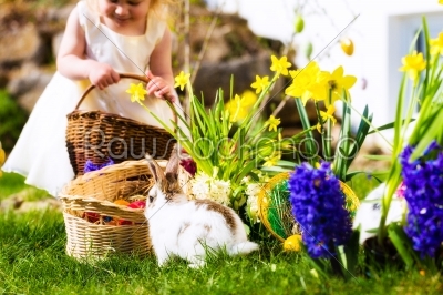 Easter Bunnies on meadow with basket and eggs