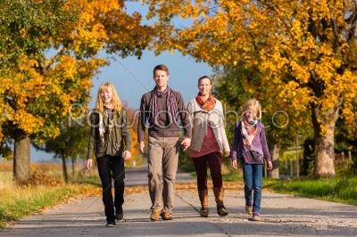 Family having walk in front of colorful trees in autumn