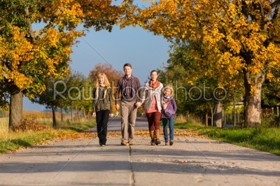 Family having walk in front of colorful trees in autumn