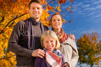 Family in front of colorful trees in autumn or 
