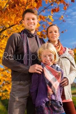 Family in front of colorful trees in autumn or 