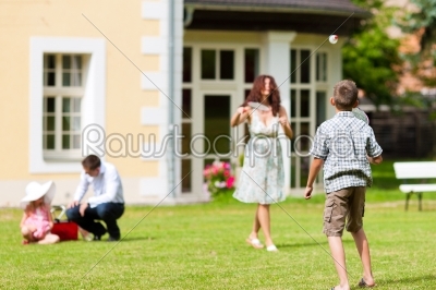 Family is playing in summer in front of their house