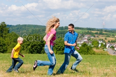 Family playing tag on meadow in summer 