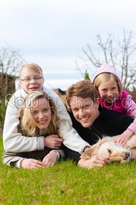 Family sits together on a meadow