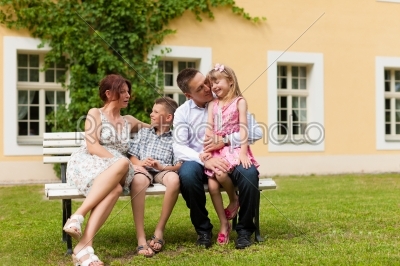 Family sitting and playing in front of their home