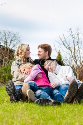 Family sitting together on a meadow in spring