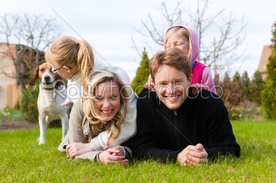 Family sitting with dogs together on a meadow