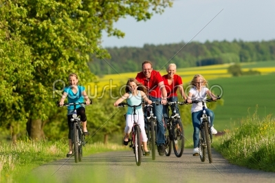 Family with kids cycling in summer with bicycles