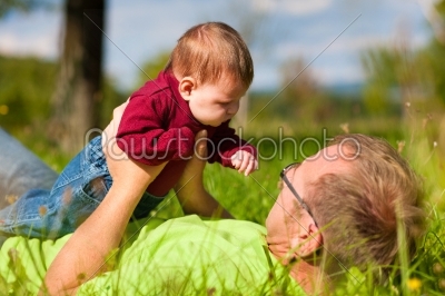 Father playing with baby on meadow