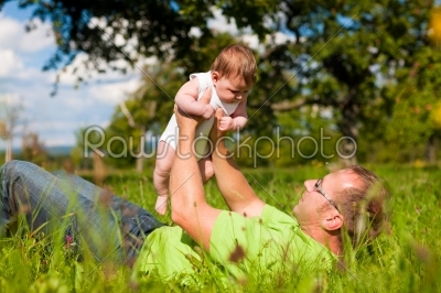 Father playing with baby on meadow