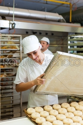 Female baker baking bread rolls