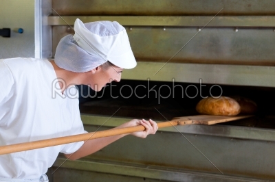 Female baker baking fresh bread in the bakehouse