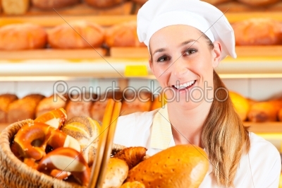 Female baker selling bread by basket in bakery