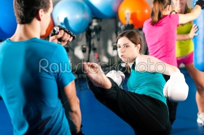 Female kick boxer with trainer in sparring