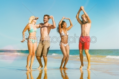 Friends jumping on ocean beach in vacation