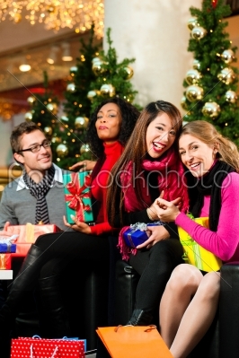 Friends with Christmas presents and bags in mall
