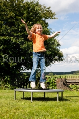 Girl child on trampoline in the garden