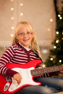 Girl with guitar in front of Christmas tree