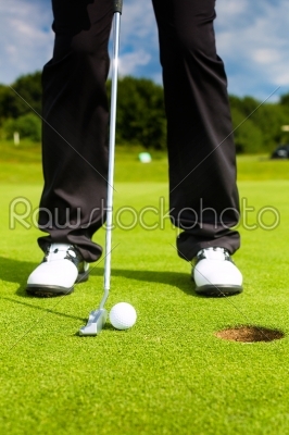 Golf player putting ball in hole