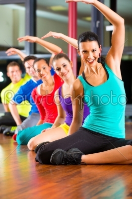 Group of people and instructor in gym stretching