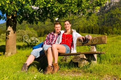 Happy Couple is sitting on a bank with mountain panorama