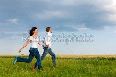 Happy couple running on a meadow