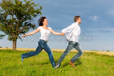 Happy couple running on a meadow
