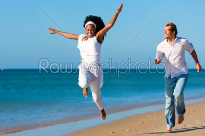 Happy couple walking and running on beach