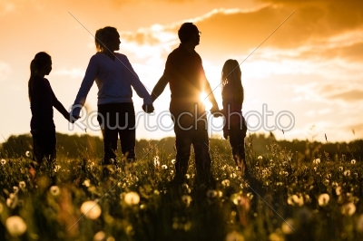 Happy family on meadow at sunset