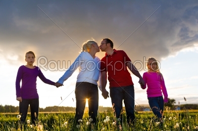 Happy family on meadow at sunset