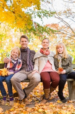 Happy Family outdoors sitting on bench in autumn