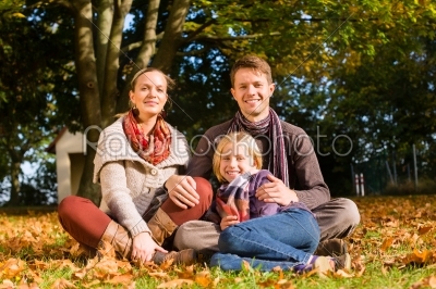 Happy Family outdoors sitting on grass in autumn