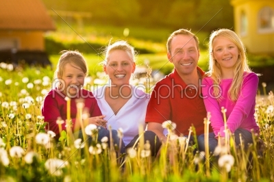 Happy family sitting in summer meadow