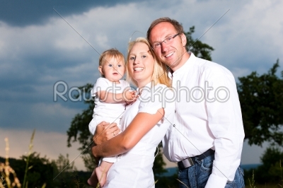 Happy family with baby in meadow