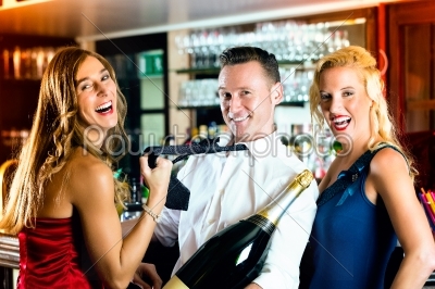 Happy friends with a bottle champagne at bar