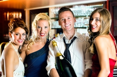 Happy friends with a bottle champagne at bar