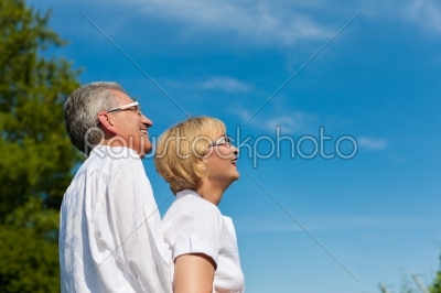 Happy mature couple or senior looking to the blue sky