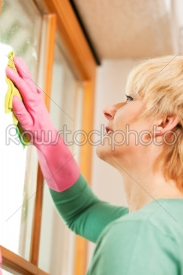 housewife cleaning her windows in rubber gloves