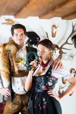 Hunter and woman in an alpine mountain hut with horn