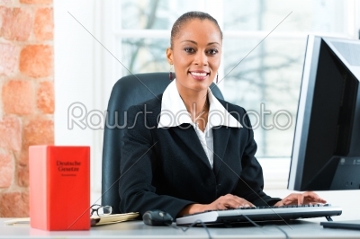 Lawyer in her office with law book on computer