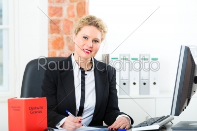 Lawyer in office with law book working on desk