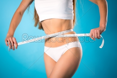Loosing weight - young woman is measuring her waist