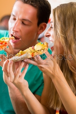 Man and woman eating a pizza